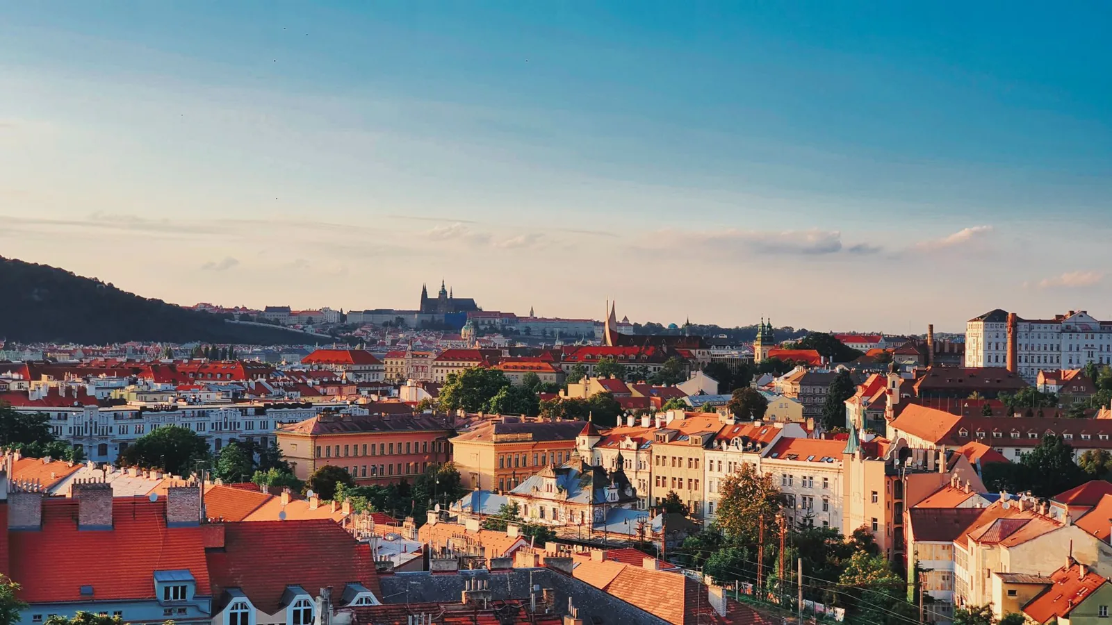 A stunning aerial view of Prague's historic rooftops and architecture under a clear blue sky.