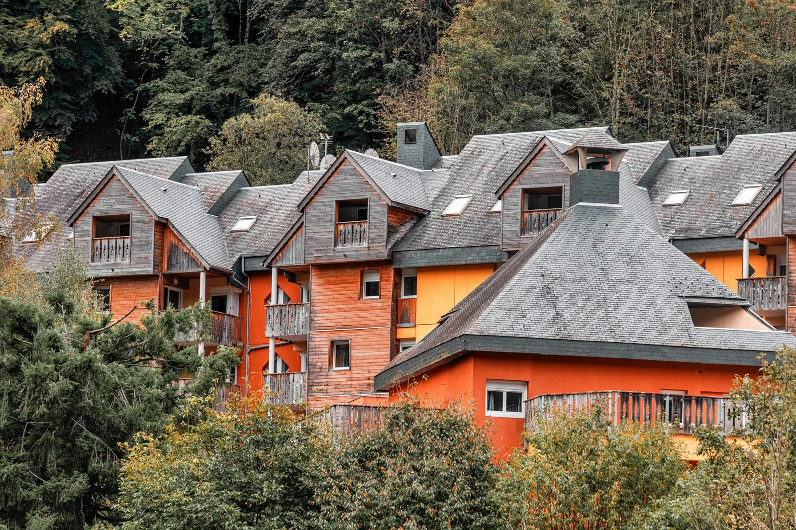 Scenic view of rustic village houses surrounded by lush greenery and forested hills.